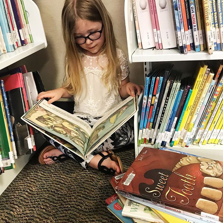 Girl reading in between two bookshelves 