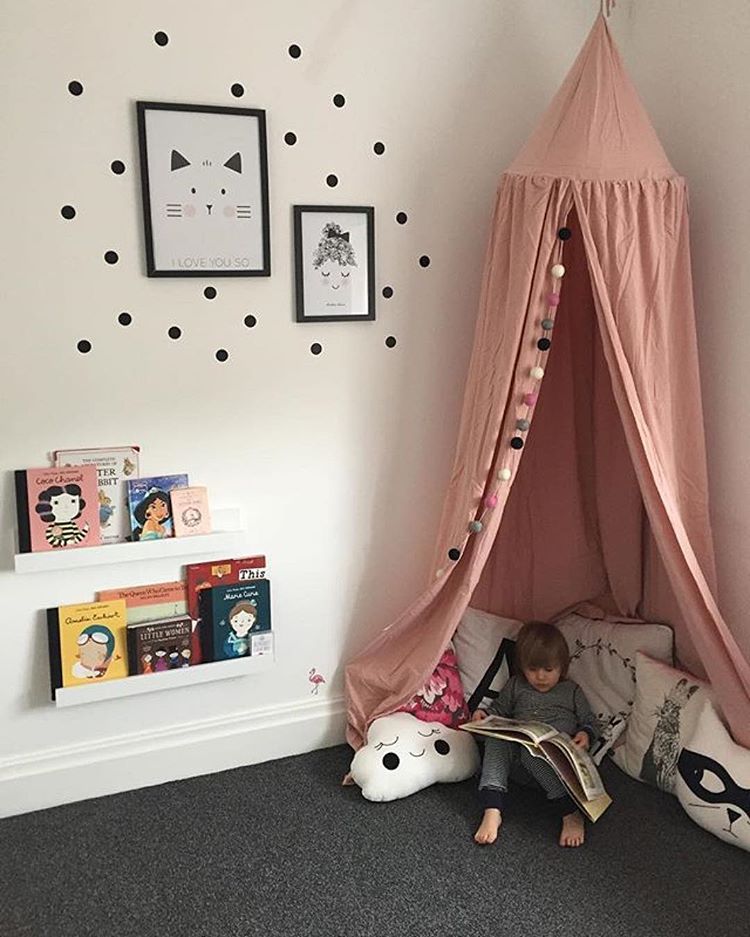 Child reading under tall pink tent in the corner of a room 