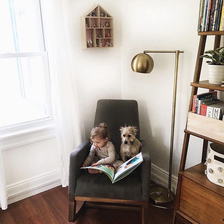 Child reading in a chair with a dog next to her