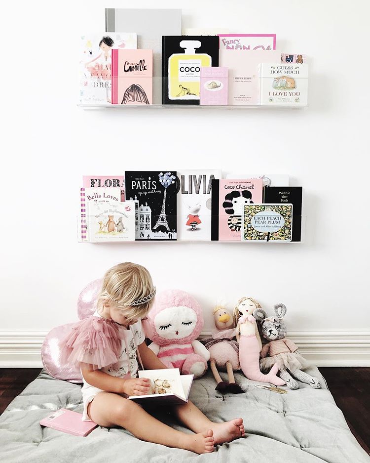Child reading under some shelves