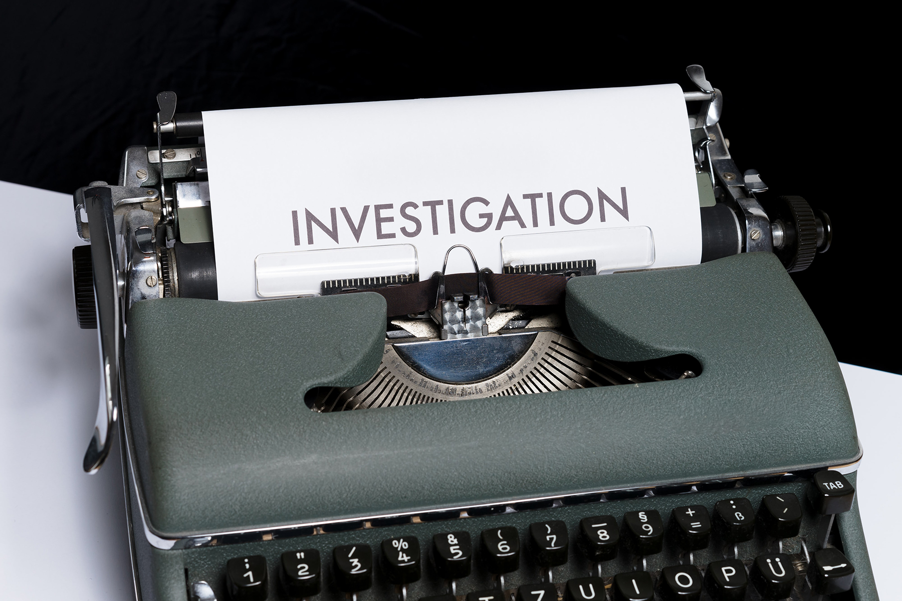 A photo of an old typewriter with a piece of paper in it and the word investigation written at the top