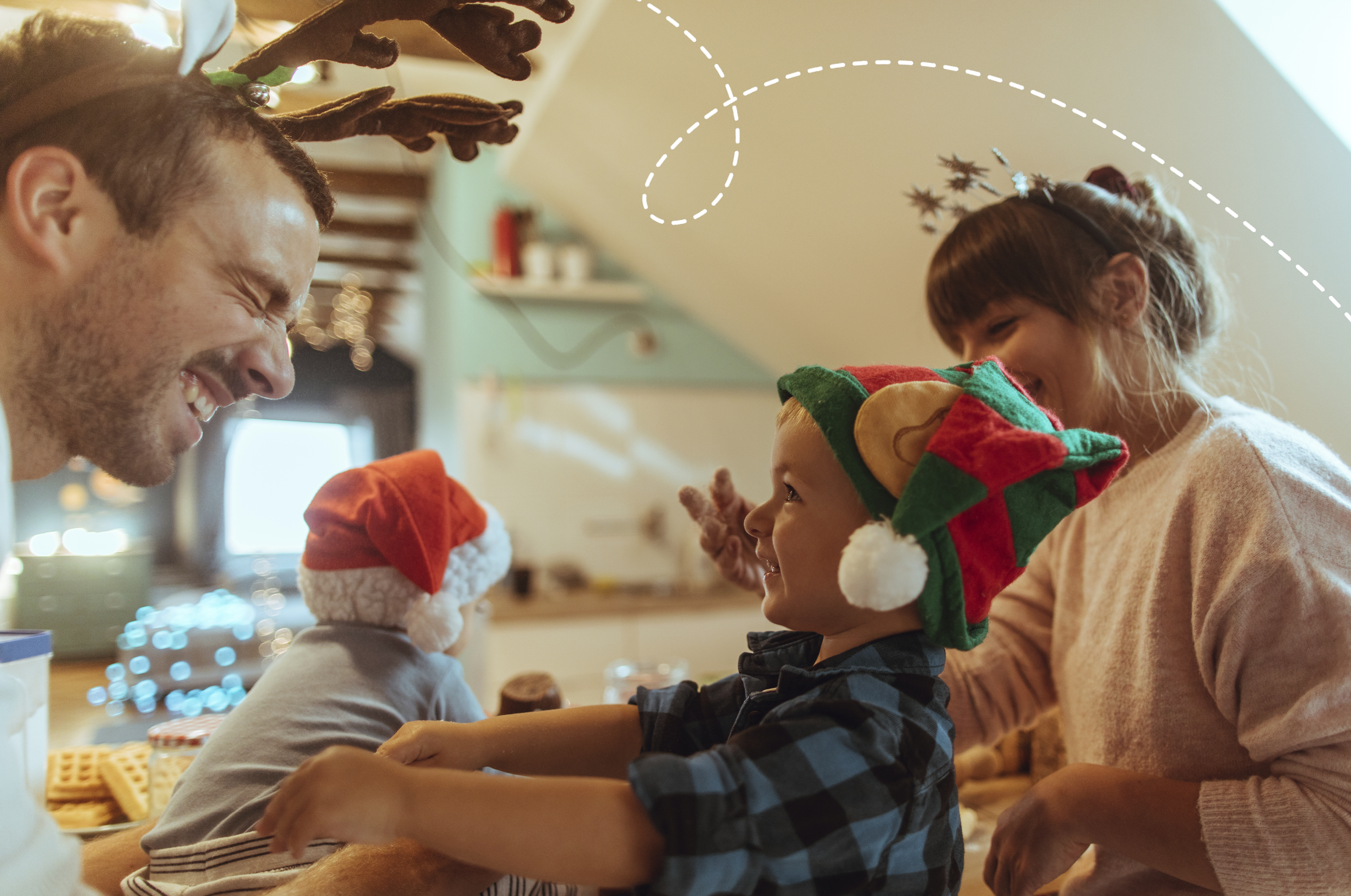 A photo of a dad making a funny face at his toddler son whilst wearing festive antlers