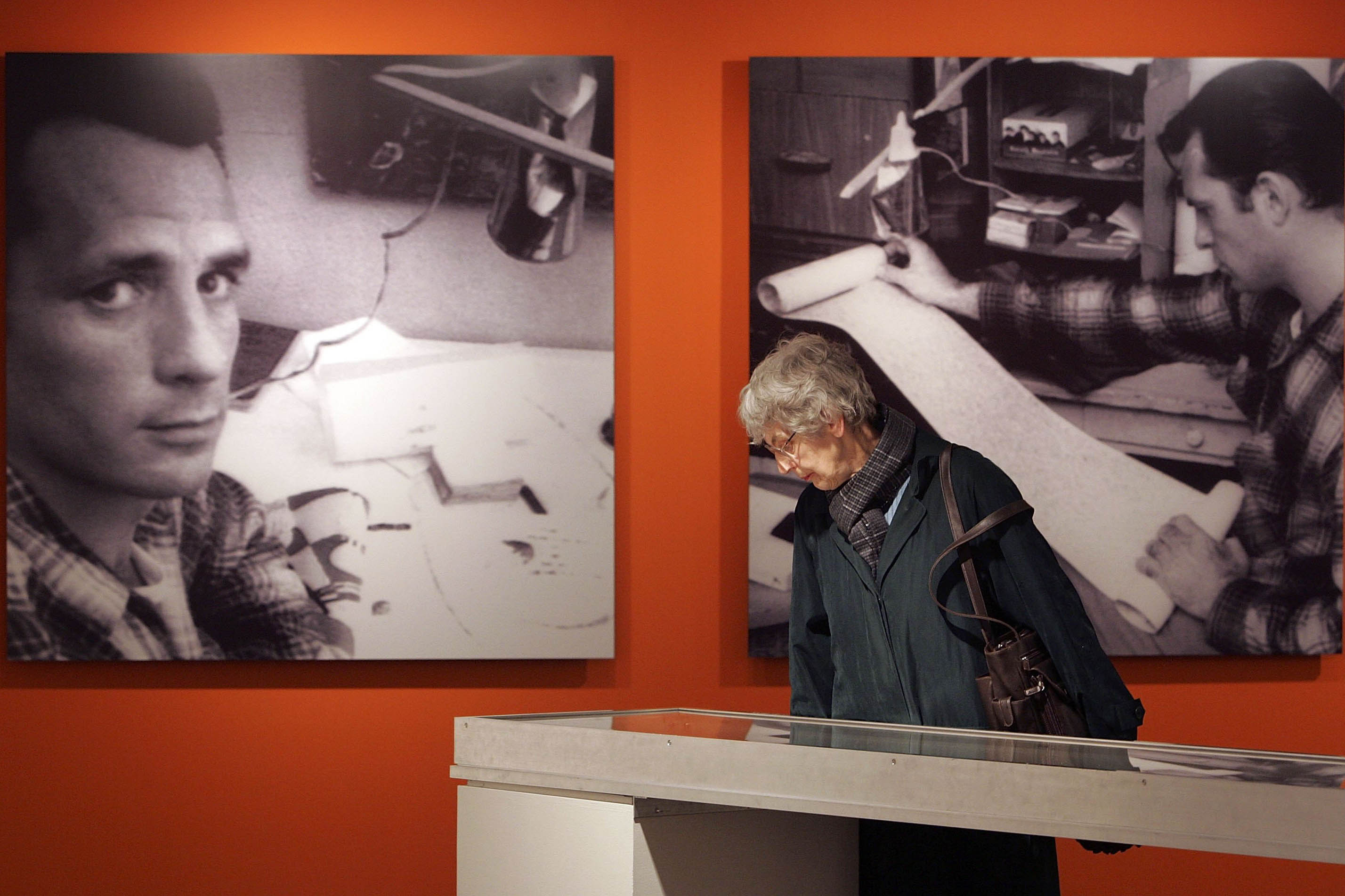 A photograph of an exhibit of Kerouac's work; there are photographs of him on the background, as a visitor looks at an exhibit.