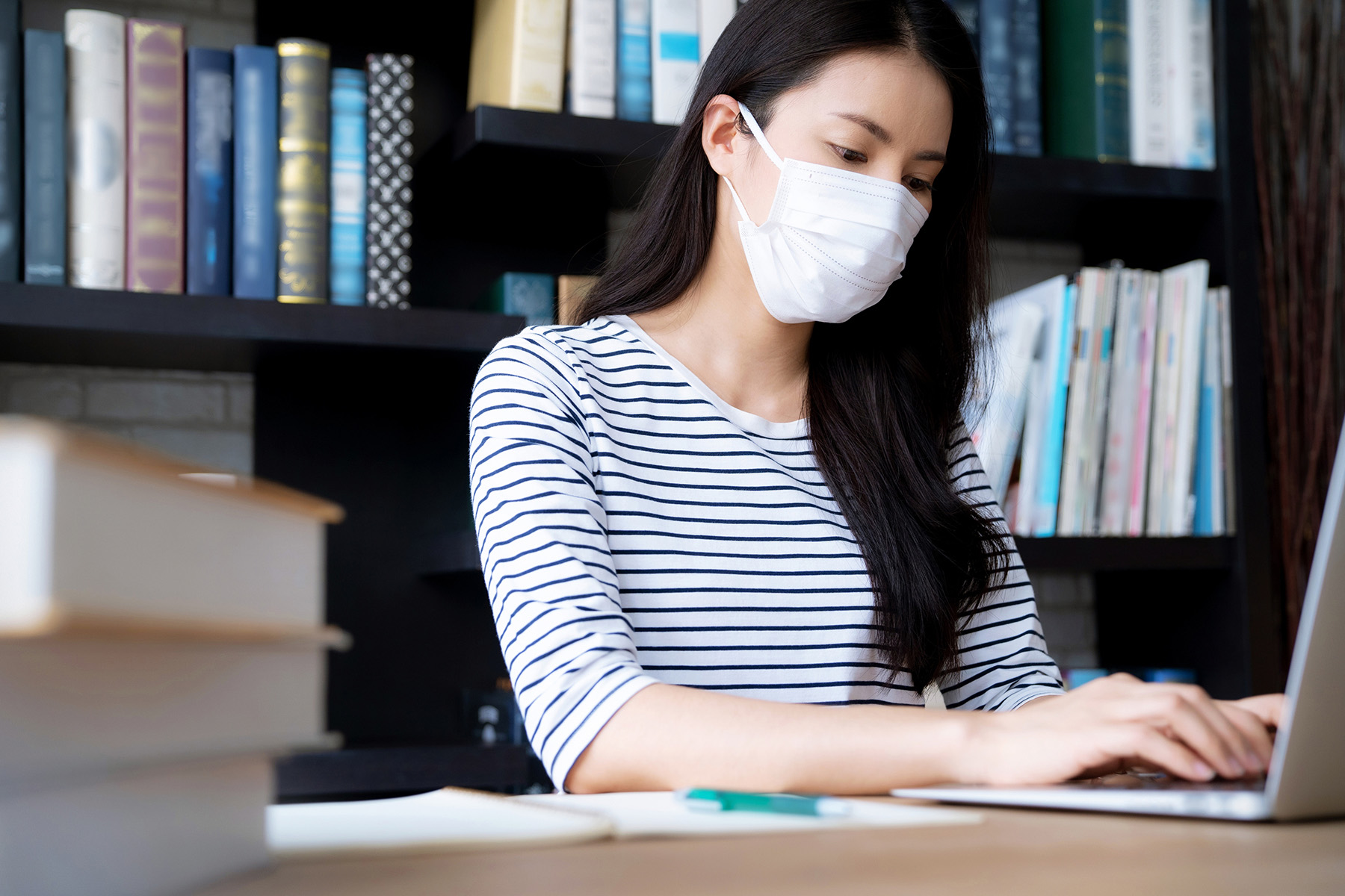 A woman wearing a face mask uses a computer at the library. Photo: iStock