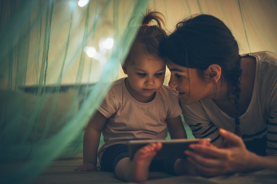 A photo of a woman and her daughter reading a book together