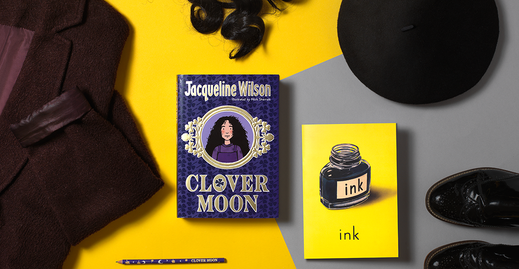 A photo of the book Clover Moon surrounded by a Victorian-style coat, boots and hat on a bright yellow background