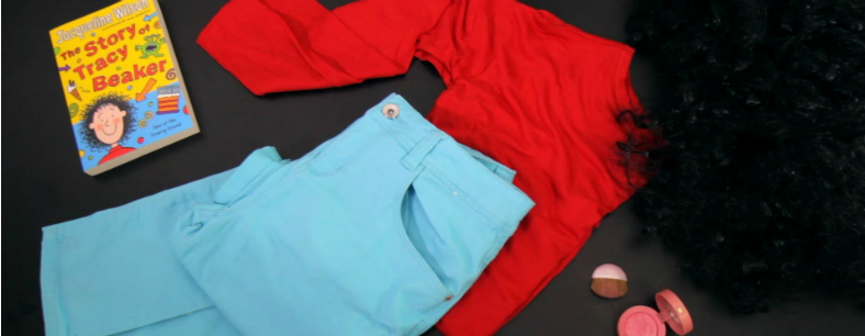 A photo of blue trousers, a red top and curly wig on a black background