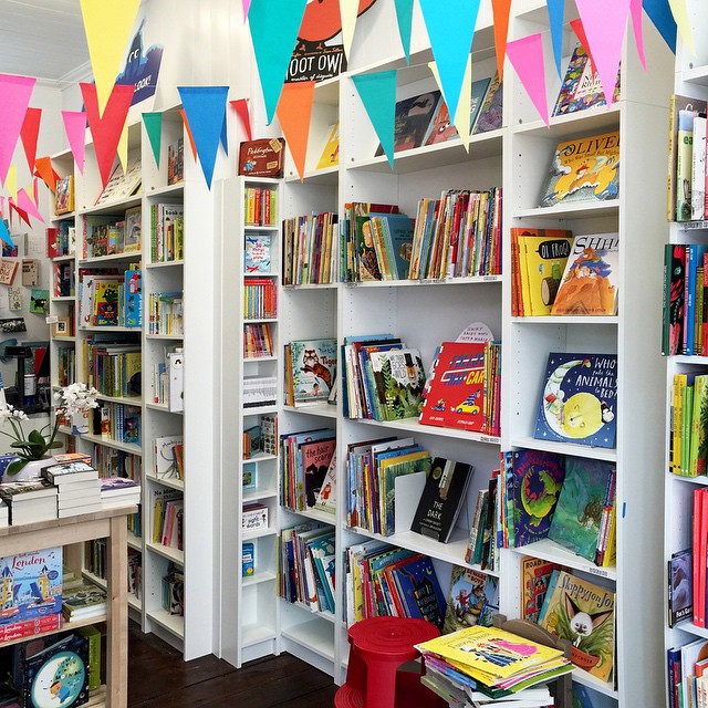 A photo of the inside of The Alligator’s Mouth Bookshop - there are books on all the shelves and bunting hung from above