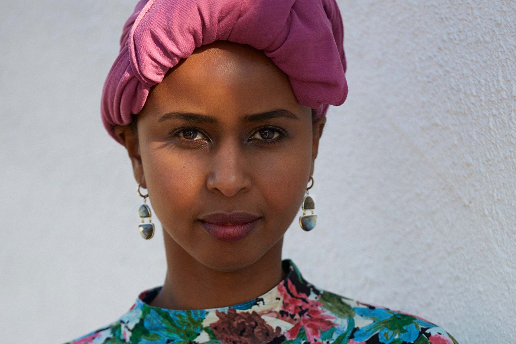 A close, head-and-shoulders portrait of Nadifa Mohamed, she is wearing a pink head scarf