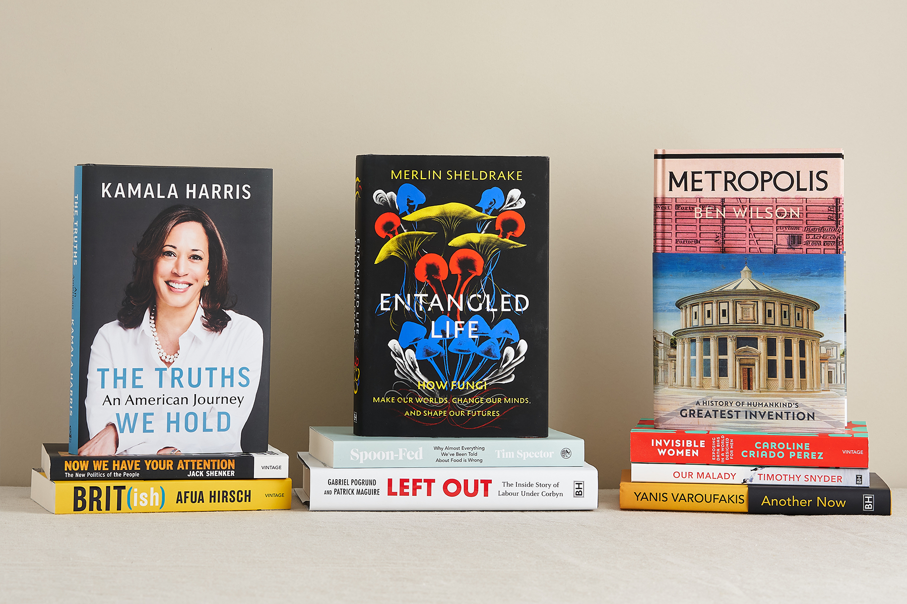 Three stacks of books, featuring The Truths We Hold by Kamala Harris, Entangled Life by Merlin Sheldrake, Metropolis by Ben Wilson