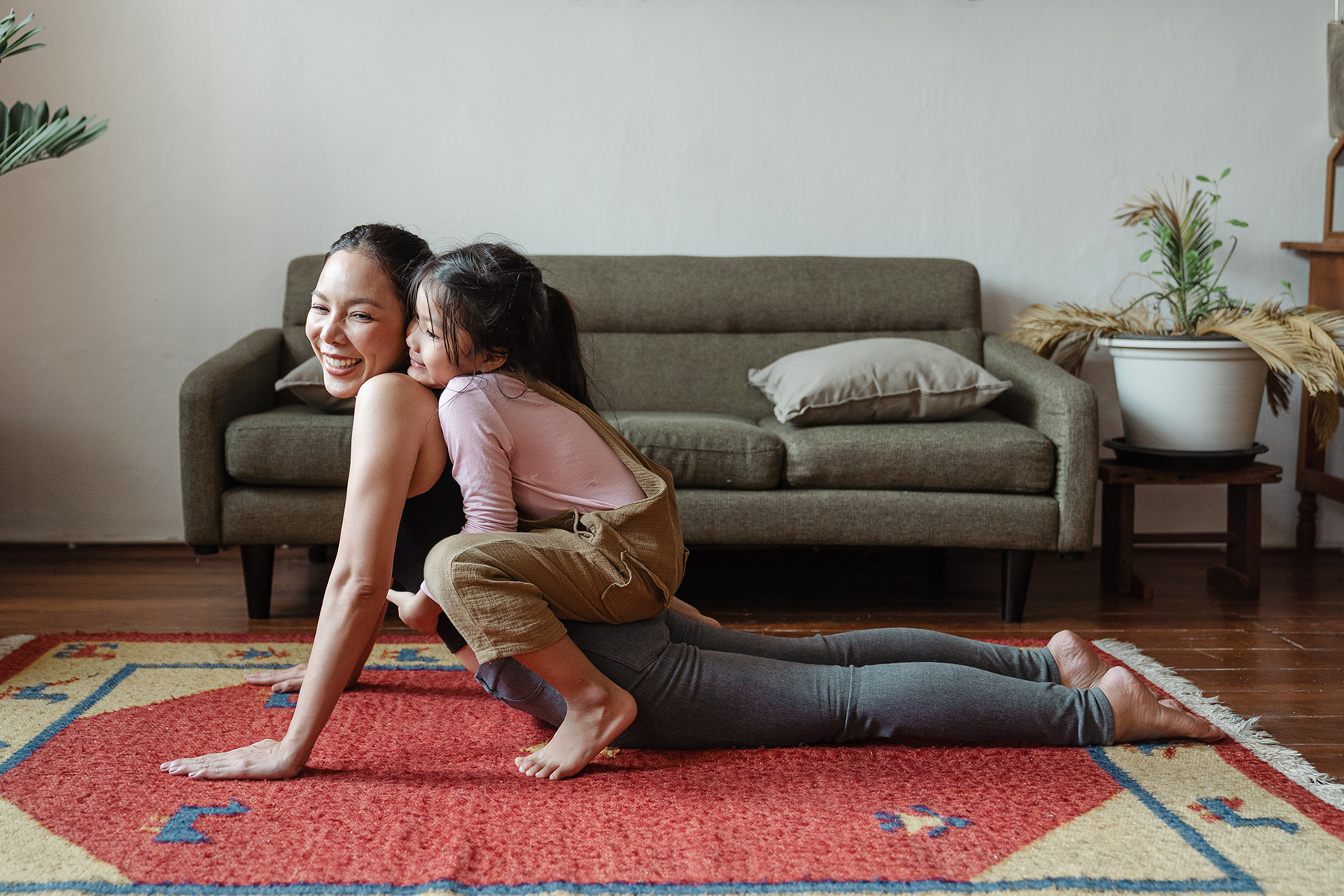 A photo of a mother and her daughter doing a yoga stretch on the floor