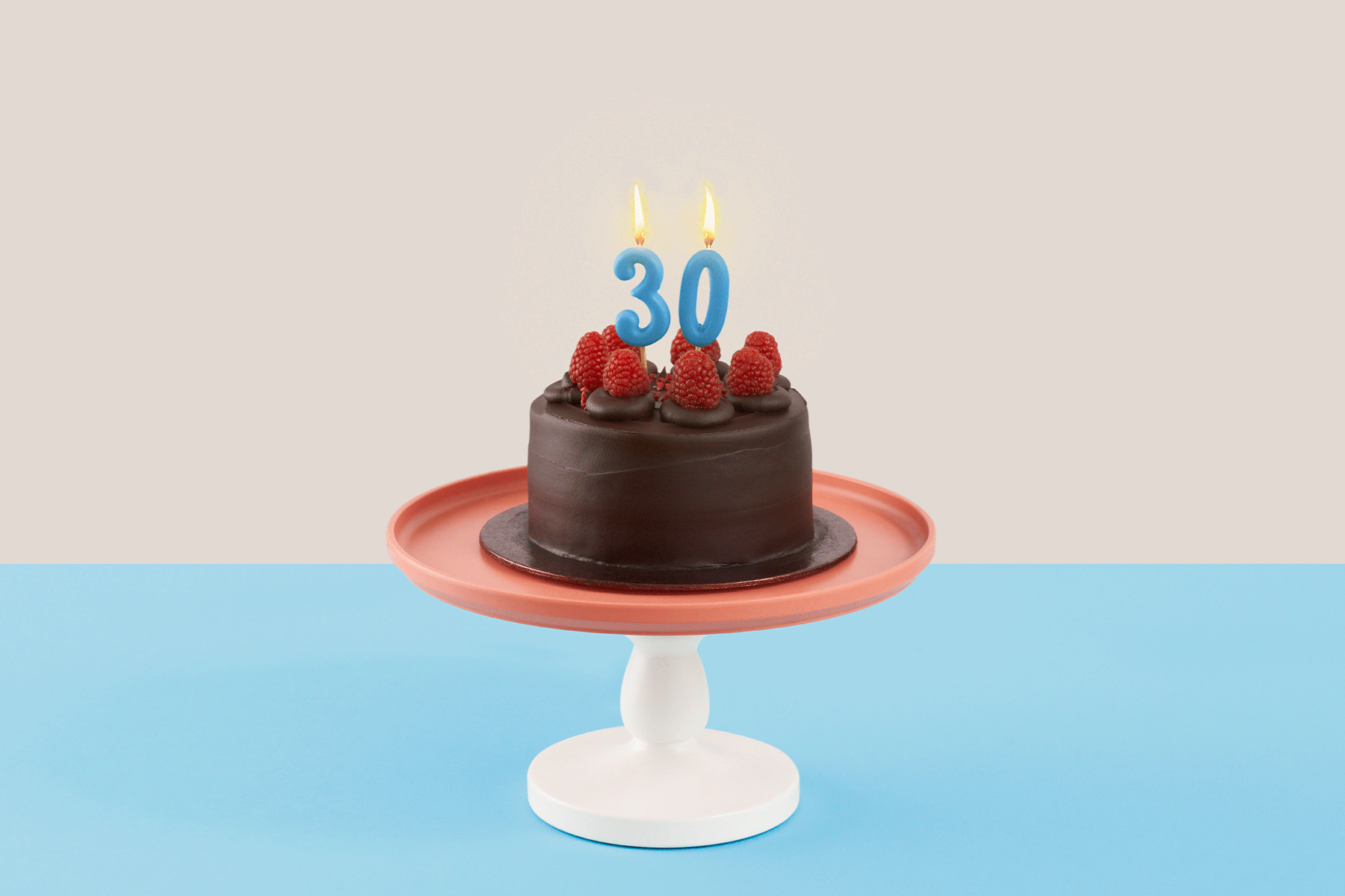 A photo of a chocolate cake with candles shaped like the number 30 atop; the candles flicker