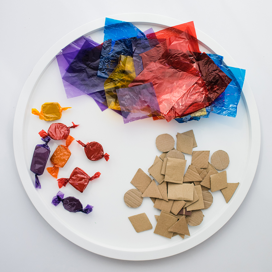 A photo of tissue paper, cardboard sweet shapes, and the sweet shapes wrapped in colourful tissue paper