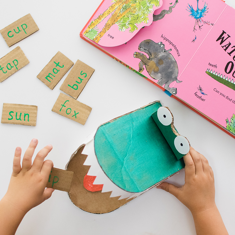 A photo of the DIY Enormous Crocodile word game. You can see a child's hands holding the cardboard crocodile and in the background is the book Roald Dahl: Words