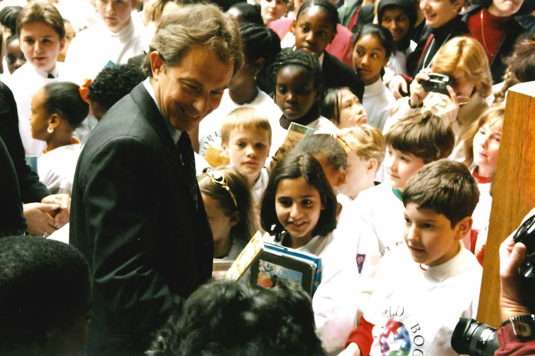 A photograph from 1997 of Tony Blair standing in the Globe theatre surrounded by school children