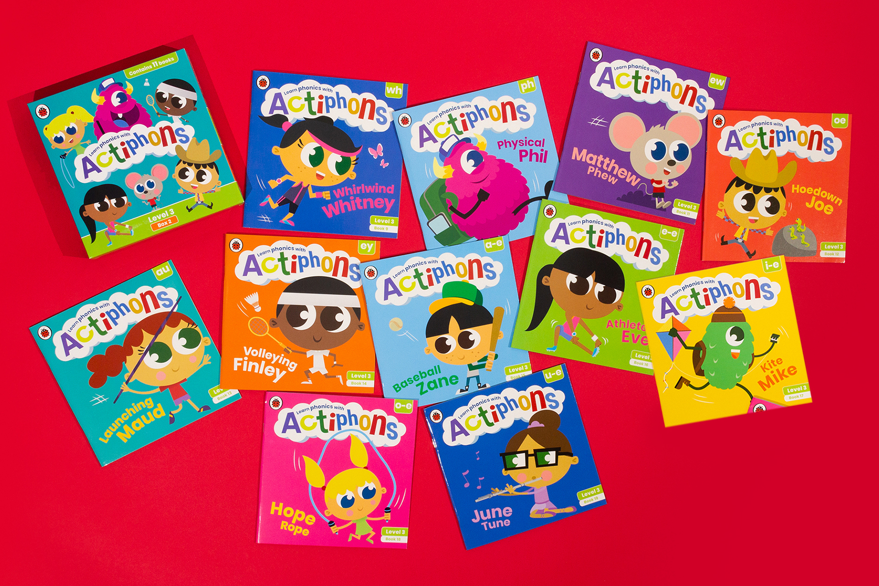 A photo of 12 books from the Actiphons series, all different reading levels, spread out on a bright red background
