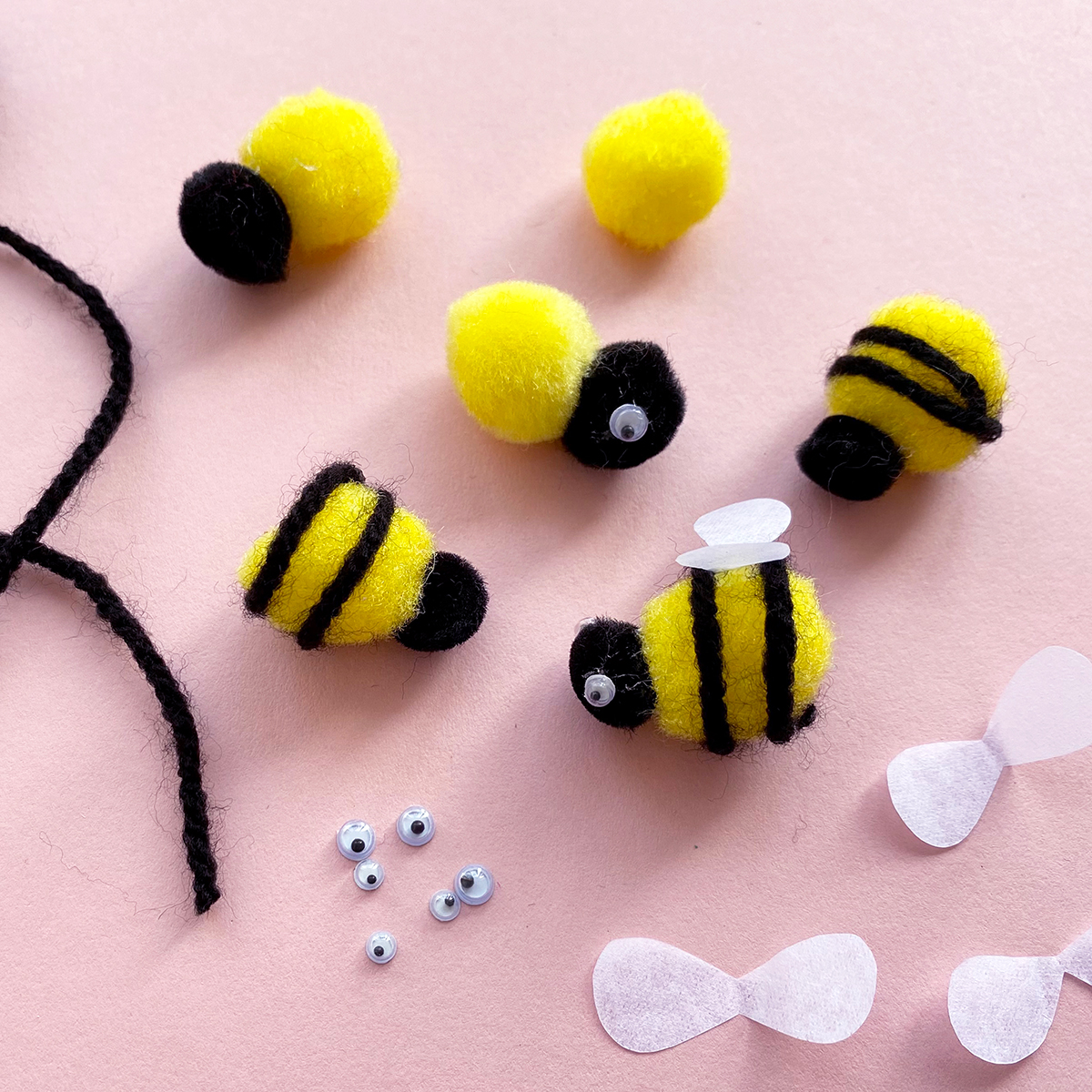 Photo to pom pom bees having wiggly eyes and paper wings stuck on with glue