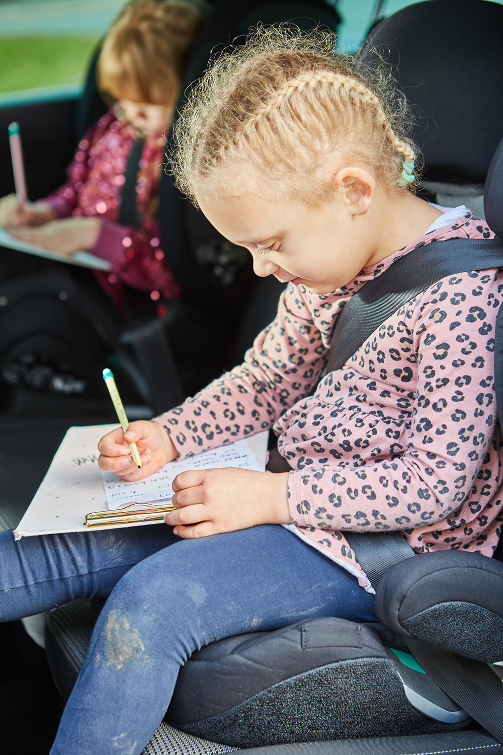 A little girl sitting in a car and marking things off a checklist