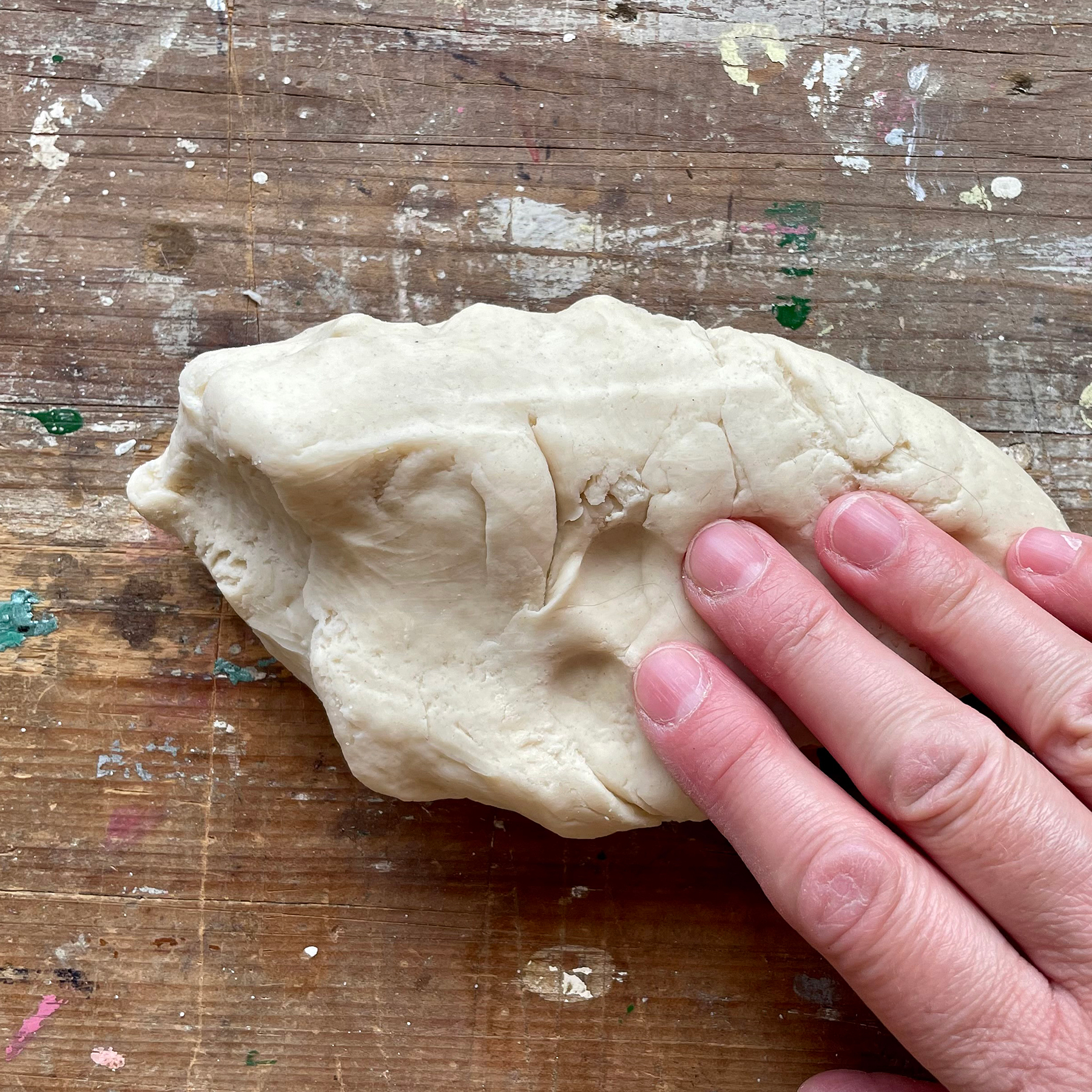 A photo of some homemade dough being kneaded by someone's fingers