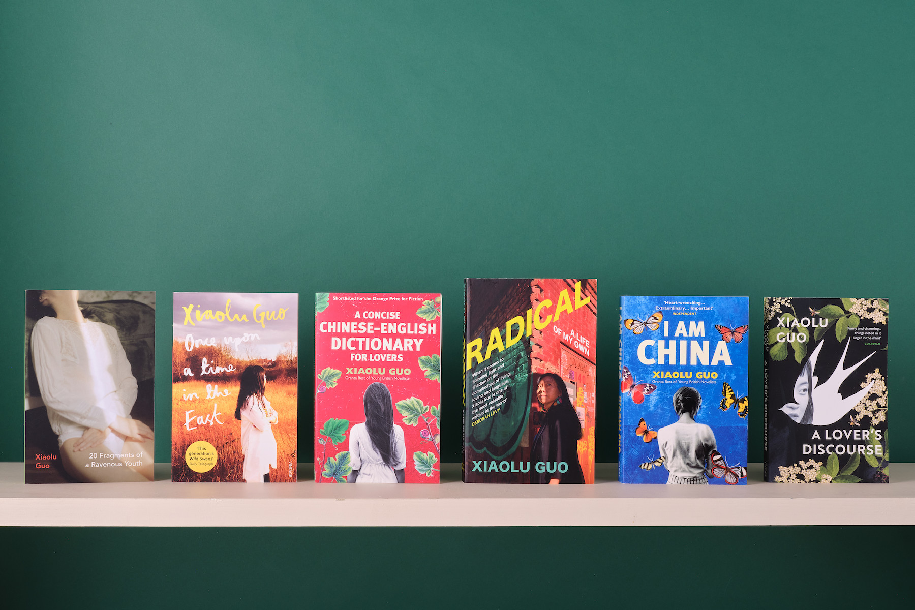 Six of Xiaolu Guo's books on a white shelf in front of a green background