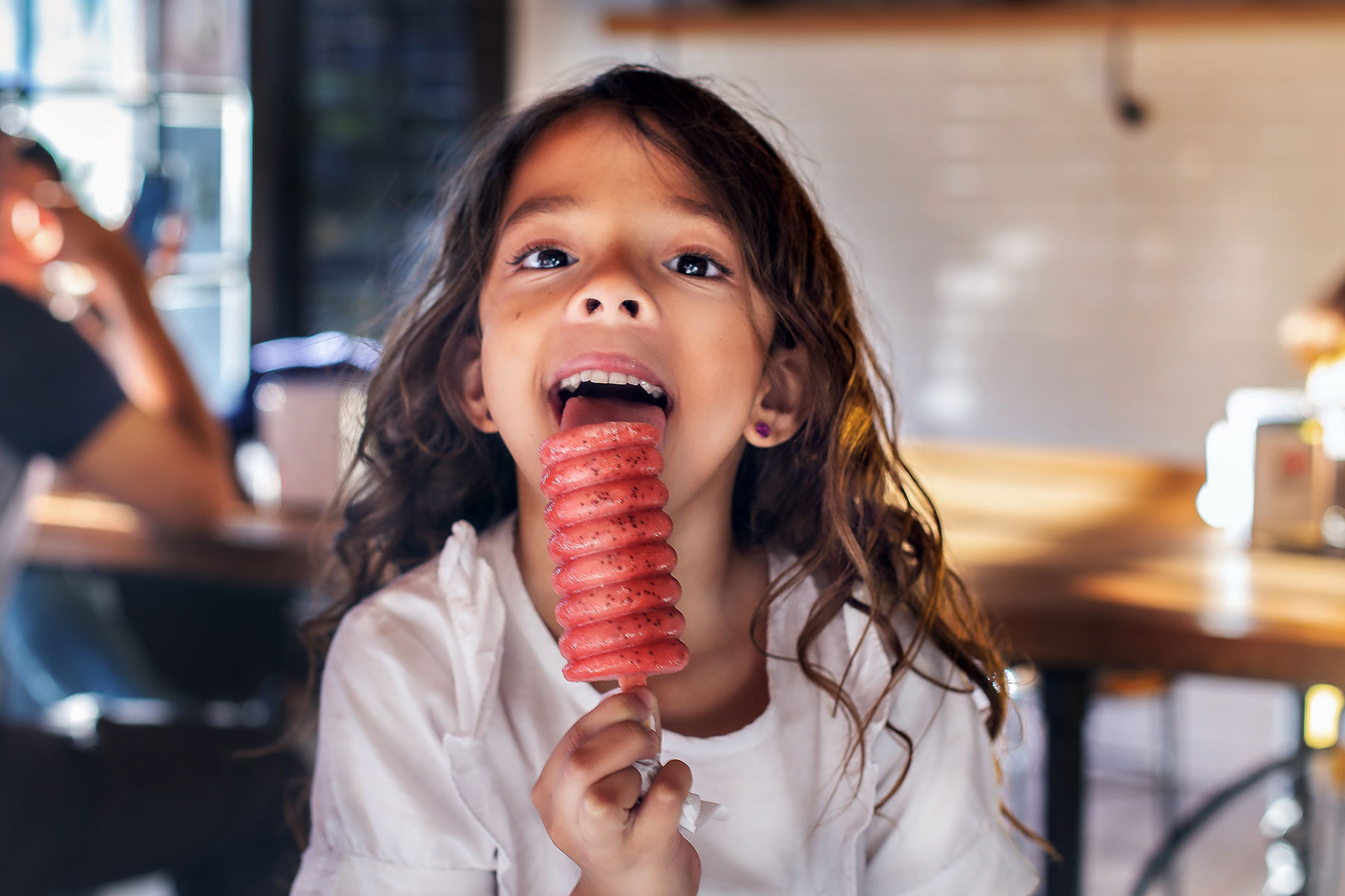 An image of a young girl licking a fruity ice lolly